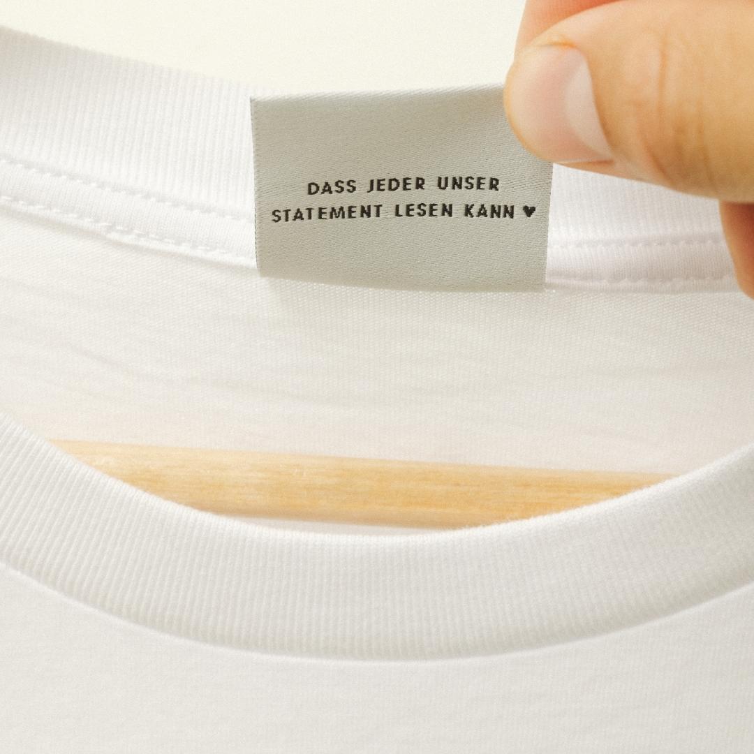 Close-Up: die Rückseite des Etikett des Feel Me T-Shirts, auf dem steht "Dass jeder unser Statement lesen kann".